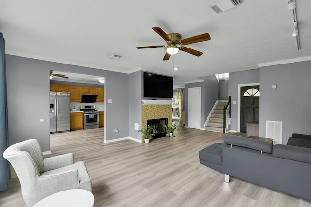 21406 Park Post Ln, Katy, TX 77450 - living room with ceiling fan, stairs, light wood finished floors, baseboards, and ornamental molding
