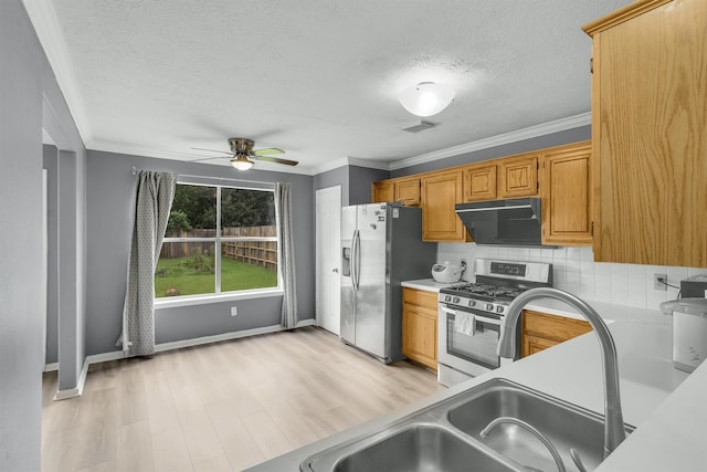 21406 Park Post Ln, Katy, TX 77450 - kitchen featuring stainless steel appliances, under cabinet range hood, a textured ceiling, a ceiling fan, and ornamental molding