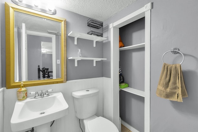 21406 Park Post Ln, Katy, TX 77450 - bathroom with a sink, toilet, wainscoting, and a textured ceiling