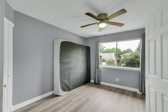 21406 Park Post Ln, Katy, TX 77450 - unfurnished bedroom with wood finished floors, baseboards, a textured ceiling, and a ceiling fan