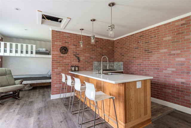 7230 Moore St, Hitchcock, TX 77563 - kitchen with a sink, baseboards, wood finished floors, brick wall, and a breakfast bar area
