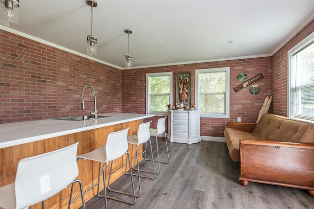 7230 Moore St, Hitchcock, TX 77563 - kitchen featuring a sink, brick wall, crown molding, wood finished floors, and baseboards
