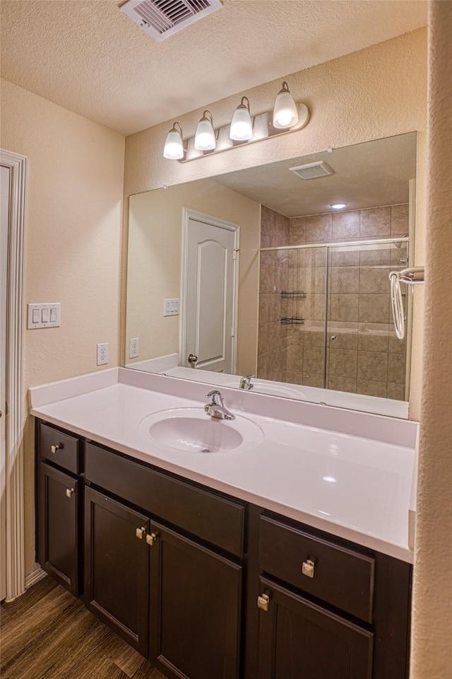 13230 Montane Manor Ln, Houston, TX 77044 - full bath with vanity, wood finished floors, tiled shower, a textured wall, and a textured ceiling