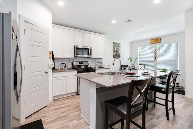 7730 Robert Ln, Rosharon, TX 77583 - kitchen with appliances with stainless steel finishes, a sink, a kitchen bar, backsplash, and light wood finished floors