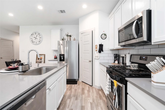 7730 Robert Ln, Rosharon, TX 77583 - kitchen featuring stainless steel appliances, a sink, light wood-style flooring, white cabinetry, and recessed lighting