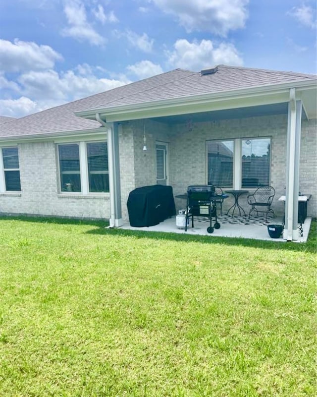 7638 Sirocco Ln, Baytown, TX 77523 - back of property with a patio area, brick siding, a shingled roof, and a lawn