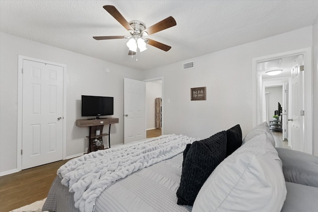 12900 Walden Rd Unit 415D, Montgomery, TX 77356 - bedroom featuring wood finished floors, ceiling fan, baseboards, attic access, and a textured ceiling