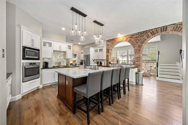 259 W Thorn Way, Houston, TX 77015 - kitchen with appliances with stainless steel finishes, a breakfast bar, white cabinetry, recessed lighting, and a textured ceiling