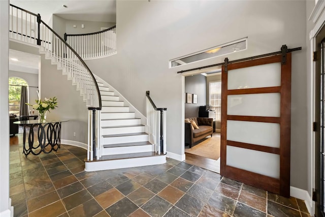 259 W Thorn Way, Houston, TX 77015 - entrance foyer with a barn door, stone tile flooring, a towering ceiling, baseboards, and stairway