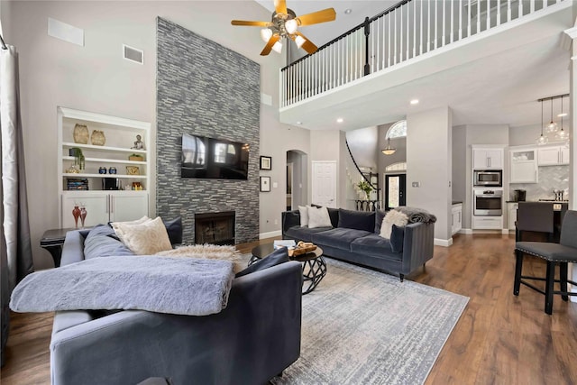 259 W Thorn Way, Houston, TX 77015 - living room featuring a towering ceiling, arched walkways, ceiling fan, a fireplace, and dark wood-type flooring