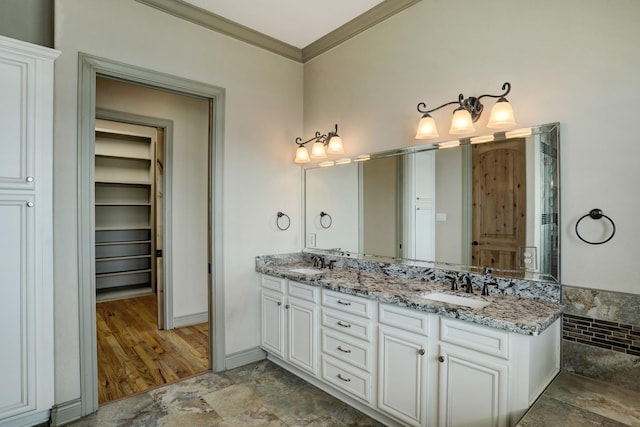 2466 Beacon Cir, League City, TX 77573 - bathroom featuring double vanity, crown molding, a spacious closet, baseboards, and stone finish flooring