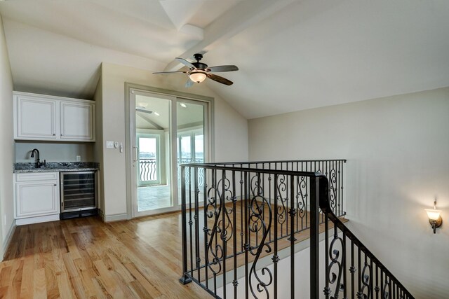 2466 Beacon Cir, League City, TX 77573 - corridor featuring wine cooler, an upstairs landing, light wood-style flooring, vaulted ceiling, and baseboards
