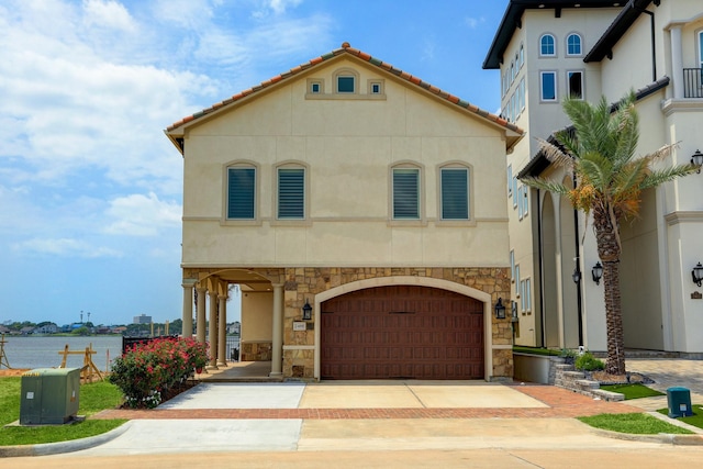 2466 Beacon Cir, League City, TX 77573 - mediterranean / spanish house featuring stone siding, an attached garage, a water view, concrete driveway, and stucco siding