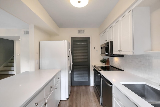 1321 Fountain View Dr Unit 131, Houston, TX 77057 - kitchen featuring stainless steel appliances, white cabinets, decorative backsplash, light countertops, and wood finished floors