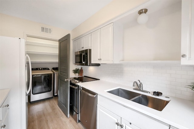 1321 Fountain View Dr Unit 131, Houston, TX 77057 - kitchen featuring separate washer and dryer, appliances with stainless steel finishes, a sink, and tasteful backsplash
