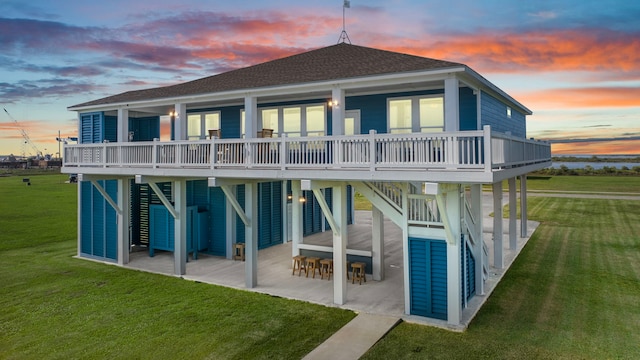 1816 Laguna Harbor Estate Blvd, Port Bolivar, TX 77650 - back of property at dusk with a patio area, a shingled roof, a yard, and a wooden deck