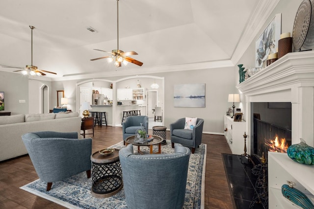 6927 Queensclub Dr, Houston, TX 77069 - living room featuring dark wood-style flooring, a ceiling fan, a lit fireplace, ornamental molding, and arched walkways