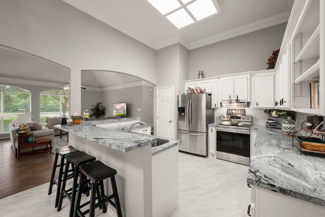 6927 Queensclub Dr, Houston, TX 77069 - kitchen with stainless steel appliances, a sink, light stone countertops, a breakfast bar area, and crown molding