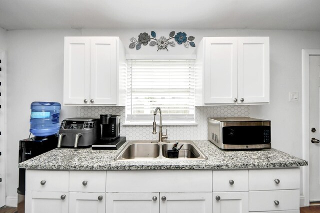 119 Burke Rd, Pasadena, TX 77506 - kitchen with stainless steel microwave, a sink, white cabinets, and decorative backsplash
