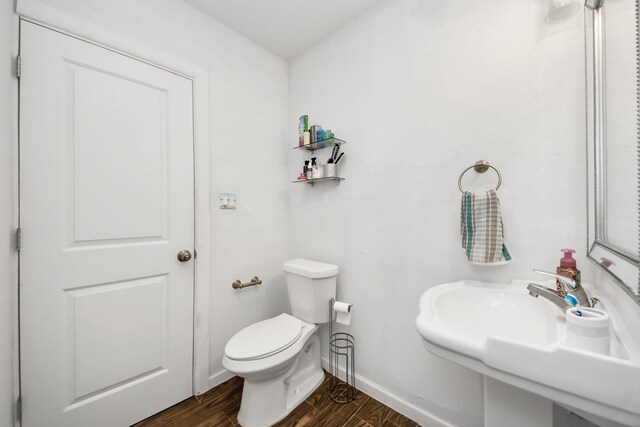 119 Burke Rd, Pasadena, TX 77506 - bathroom featuring wood finished floors, baseboards, toilet, and a sink