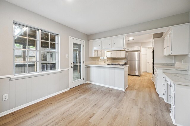 1802 Corral Dr, Houston, TX 77090 - kitchen with freestanding refrigerator, a peninsula, light wood-style floors, light countertops, and white cabinetry