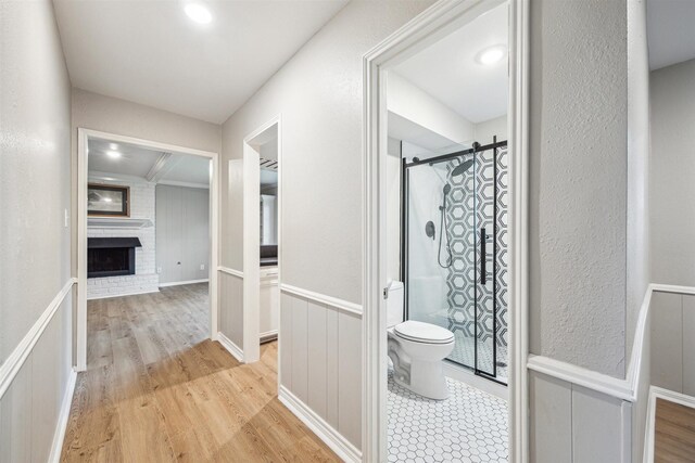 1802 Corral Dr, Houston, TX 77090 - bathroom featuring toilet, a stall shower, wood finished floors, a decorative wall, and wainscoting
