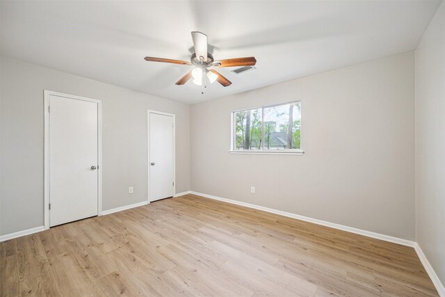 1802 Corral Dr, Houston, TX 77090 - unfurnished bedroom with light wood finished floors, baseboards, ceiling fan, and multiple closets