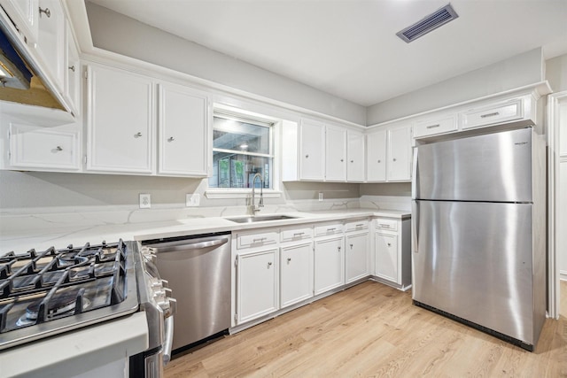 1802 Corral Dr, Houston, TX 77090 - kitchen with stainless steel appliances, a sink, white cabinets, and light wood-type flooring
