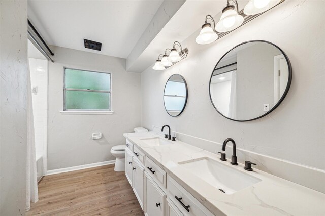 1802 Corral Dr, Houston, TX 77090 - full bathroom with double vanity, toilet, wood finished floors, shower / tub combo with curtain, and baseboards