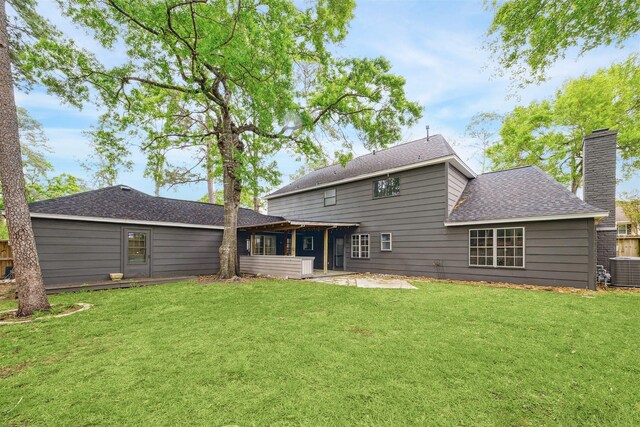 1802 Corral Dr, Houston, TX 77090 - rear view of house featuring a lawn, a patio area, a shingled roof, a chimney, and central AC unit