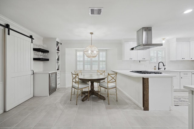10043 Overbrook Ln, Houston, TX 77042 - kitchen with range hood, healthy amount of natural light, a barn door, white cabinets, and crown molding