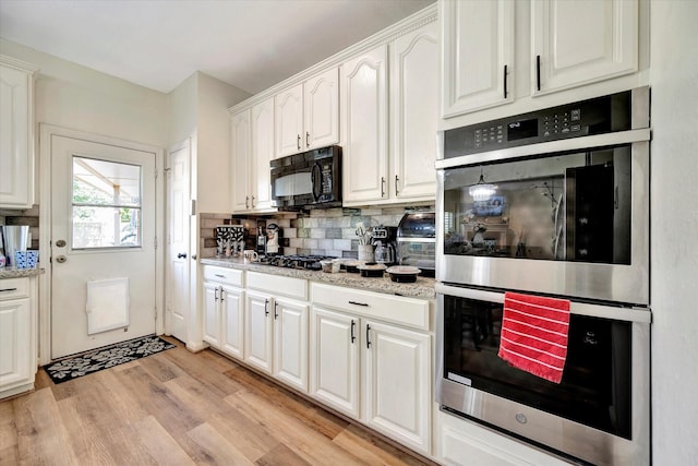 3602 Garrettsville Dr, Pearland, TX 77584 - kitchen with appliances with stainless steel finishes, white cabinetry, decorative backsplash, light wood-style floors, and light stone countertops