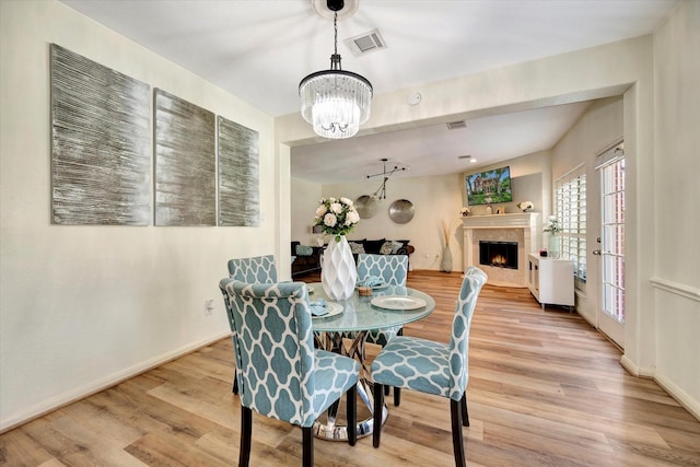 3602 Garrettsville Dr, Pearland, TX 77584 - dining room with wood finished floors, a chandelier, a high end fireplace, and baseboards