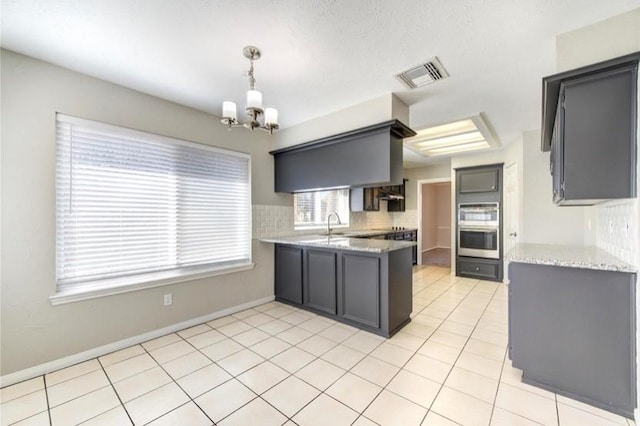 3838 Fawn Creek Dr, Houston, TX 77339 - kitchen featuring stainless steel double oven, a peninsula, a chandelier, light stone countertops, and backsplash