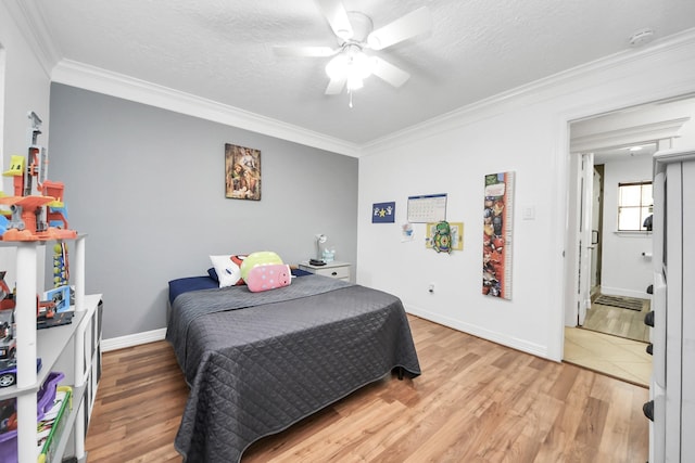 24 Woody Creek Dr, Conroe, TX 77301 - bedroom featuring crown molding, light wood-type flooring, baseboards, a textured ceiling, and ceiling fan