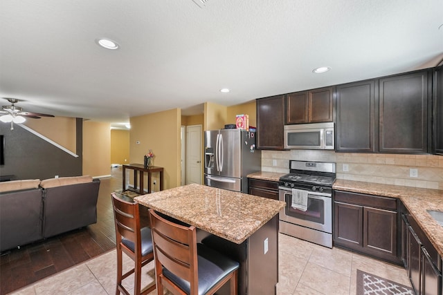 15426 Hope Shadow Ct, Cypress, TX 77429 - kitchen featuring appliances with stainless steel finishes, a center island, open floor plan, ceiling fan, and backsplash