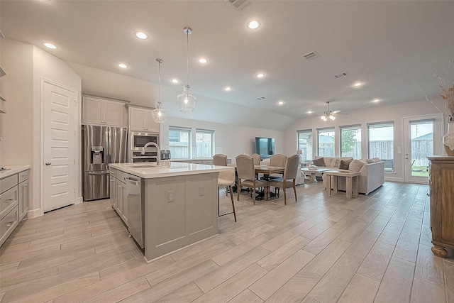 29042 Hauter Way, Fulshear, TX 77441 - kitchen featuring appliances with stainless steel finishes, a sink, open floor plan, light wood finished floors, and lofted ceiling