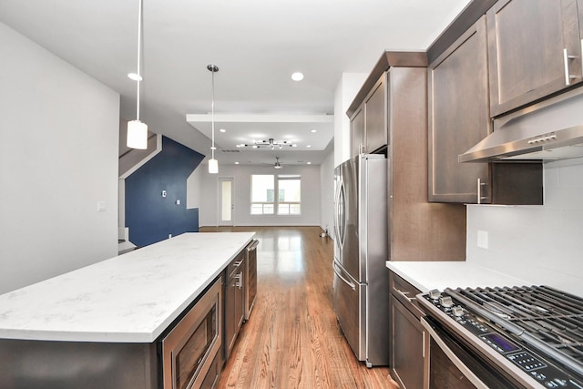 310 Eado Park Cir, Houston, TX 77020 - kitchen with stainless steel appliances, light wood finished floors, dark brown cabinets, a kitchen island, and recessed lighting