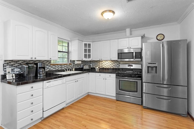 5614 Whipporwill Rd, Conroe, TX 77303 - kitchen featuring appliances with stainless steel finishes, ornamental molding, a sink, a textured ceiling, and white cabinets