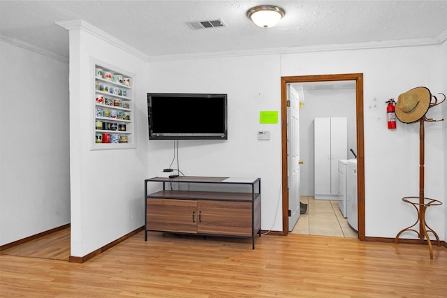 5614 Whipporwill Rd, Conroe, TX 77303 - living area with separate washer and dryer, wood finished floors, ornamental molding, a textured ceiling, and baseboards