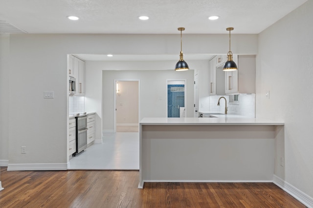 3734 Florinda St, Houston, TX 77021 - kitchen featuring appliances with stainless steel finishes, backsplash, wood finished floors, decorative light fixtures, and light countertops