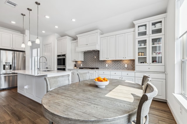 15003 Big Spring Park Dr, Cypress, TX 77433 - kitchen featuring stainless steel appliances, a center island with sink, tasteful backsplash, light countertops, and dark wood-style floors