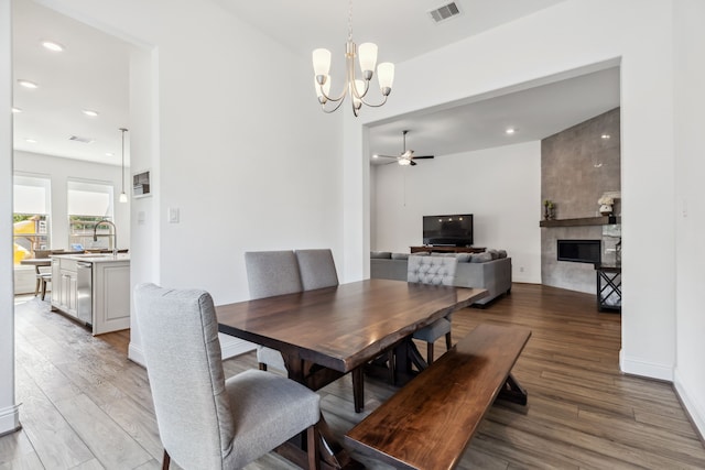 15003 Big Spring Park Dr, Cypress, TX 77433 - dining space with light wood finished floors, a tile fireplace, a chandelier, ceiling fan, and recessed lighting