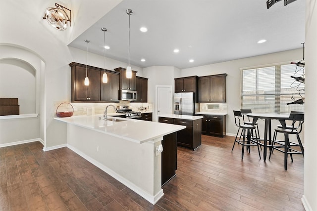 17040 Shy Leaf Ct, Conroe, TX 77385 - kitchen featuring appliances with stainless steel finishes, a sink, a kitchen island, dark brown cabinets, and dark wood-style flooring