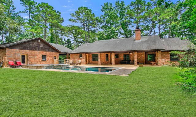 22402 Timber Ridge Dr, Magnolia, TX 77355 - back of house featuring a patio area, a yard, a chimney, brick siding, and a pool with connected hot tub