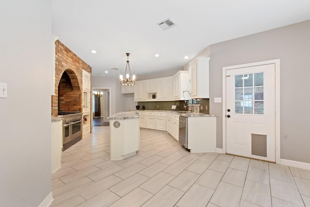 22402 Timber Ridge Dr, Magnolia, TX 77355 - kitchen featuring stainless steel appliances, a chandelier, a sink, a kitchen island, and light stone counters