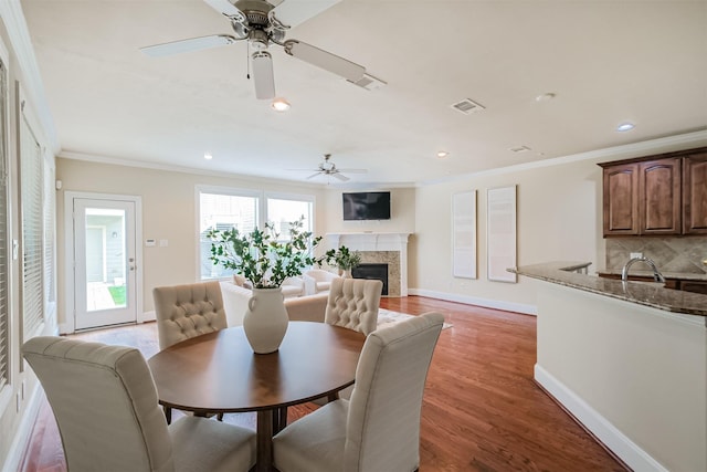 231 W 26th St, Houston, TX 77008 - dining room featuring ceiling fan, a fireplace, ornamental molding, baseboards, and light wood-style flooring