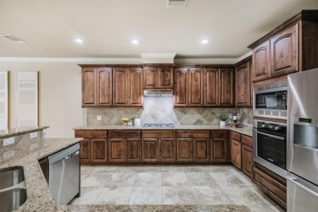 231 W 26th St, Houston, TX 77008 - kitchen with appliances with stainless steel finishes, crown molding, light stone counters, backsplash, and under cabinet range hood