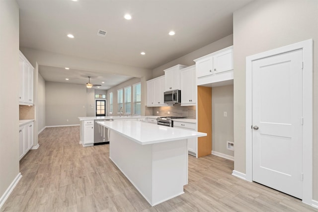 119 Lukewood Cir, Conroe, TX 77318 - kitchen featuring appliances with stainless steel finishes, a peninsula, white cabinets, decorative backsplash, and recessed lighting