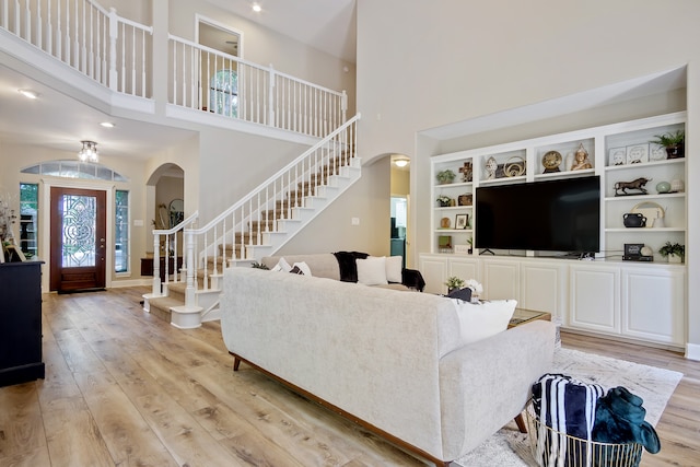 3006 Pecan Way Ct, Richmond, TX 77406 - living room with arched walkways, stairway, light wood-style floors, and a towering ceiling